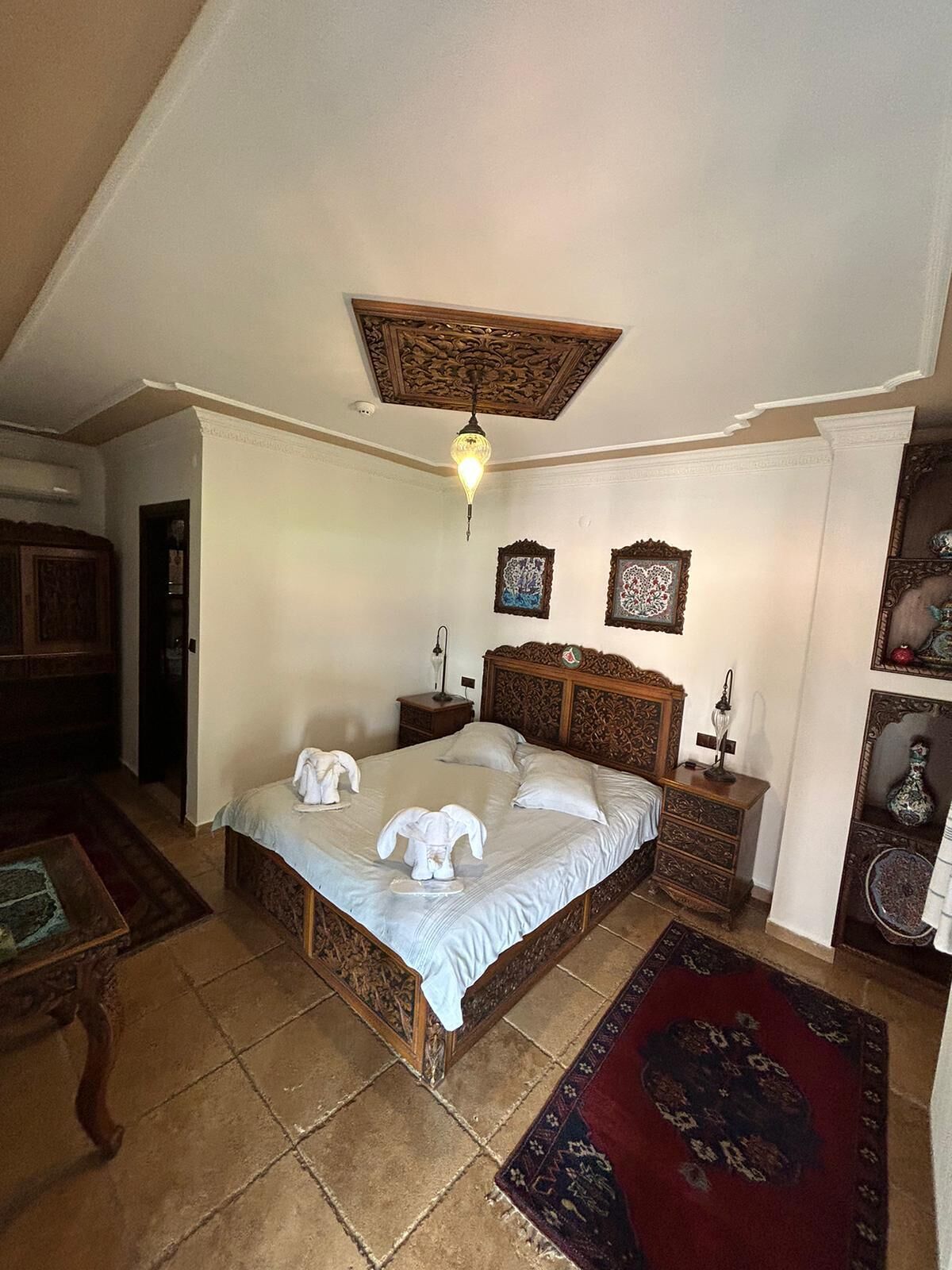 Een slaapkamer met een houten bed, een nachtkastje, een dressoir en een plafondlamp.