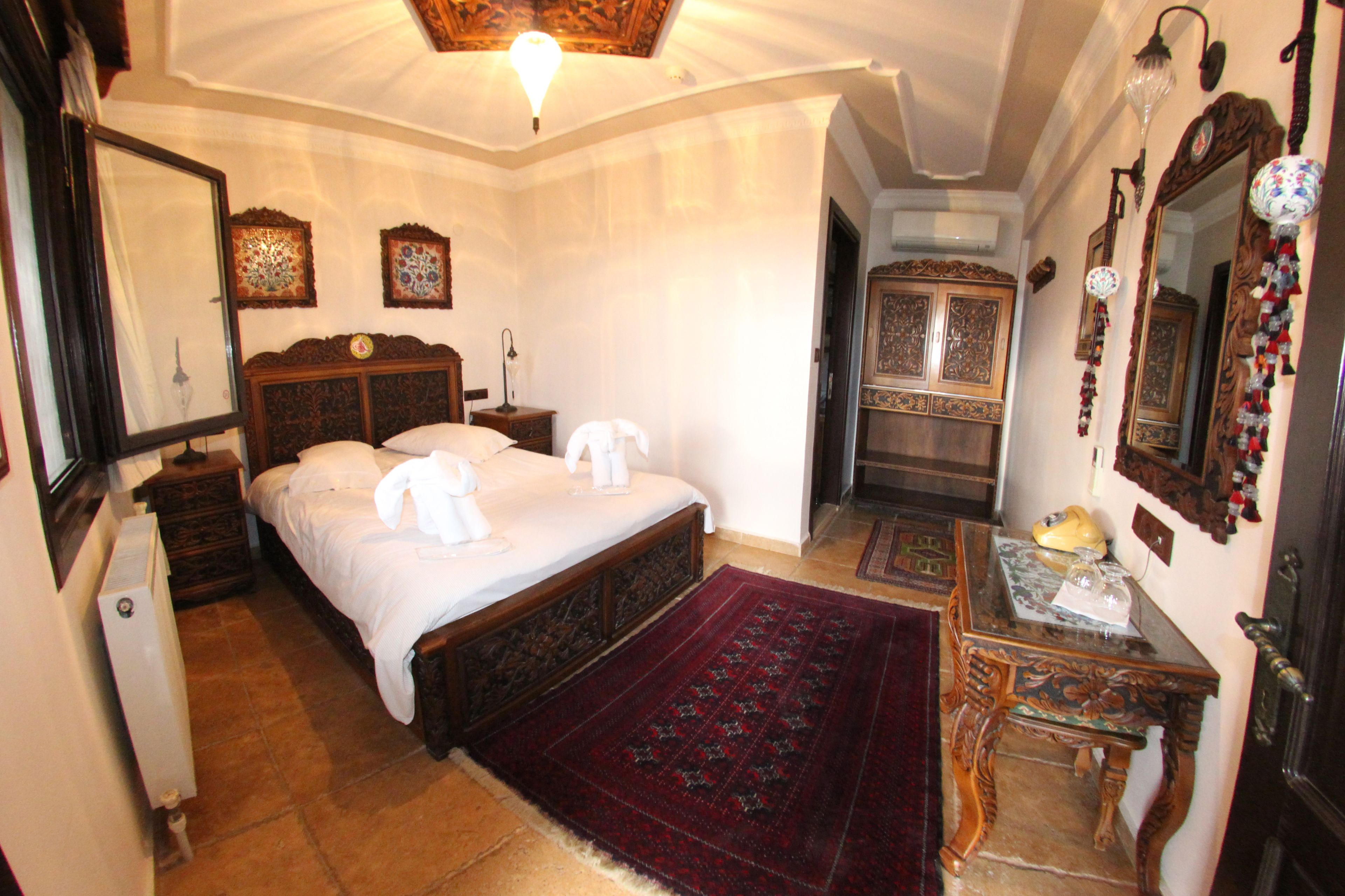 A traditional bedroom with a large bed, a wooden nightstand, a dresser, and a mirror.