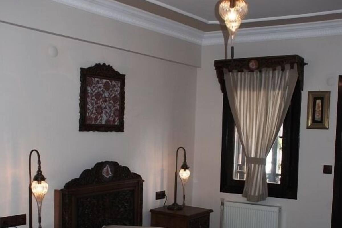 Un dormitorio con dos camas, cabeceros de madera, una ventana con cortinas y un radiador.