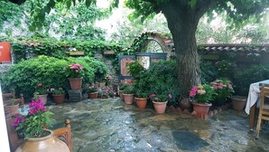 A stone-paved courtyard with potted plants and a wooden table. - Hotel Nilya - Special Class (Selçuk)