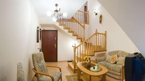A living room with a wooden staircase, a sofa, a coffee table, and a television. - VISITzakopane Rainbow Apartments (Zakopane)