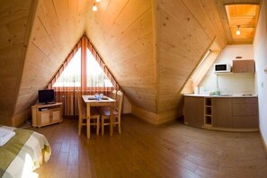 A cozy, wooden-paneled room with a dining table, chairs, a TV, and a kitchenette. - VISITzakopane City Apartments (Zakopane)