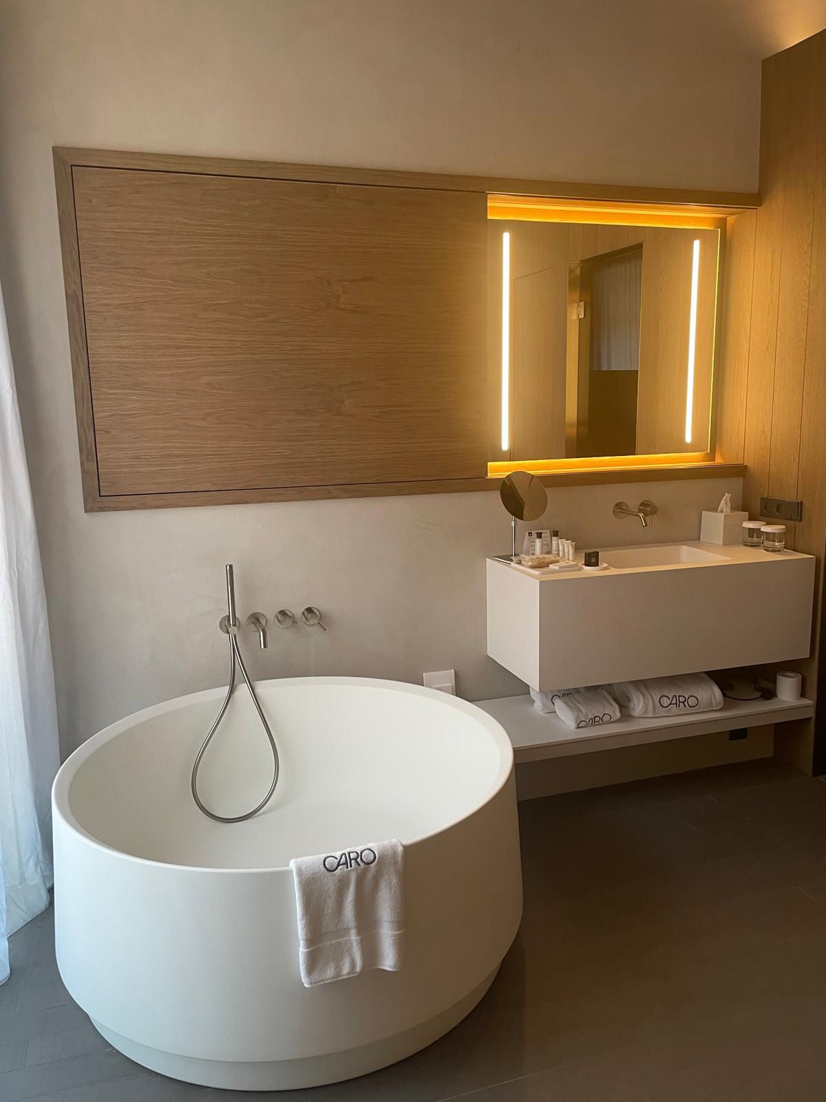 Casa de banho moderna com uma grande pia redonda, um espelho e toucador com porta-toalhas.