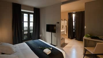 Een hotelkamer met een bed, een televisie, een bureau en een badkamer.