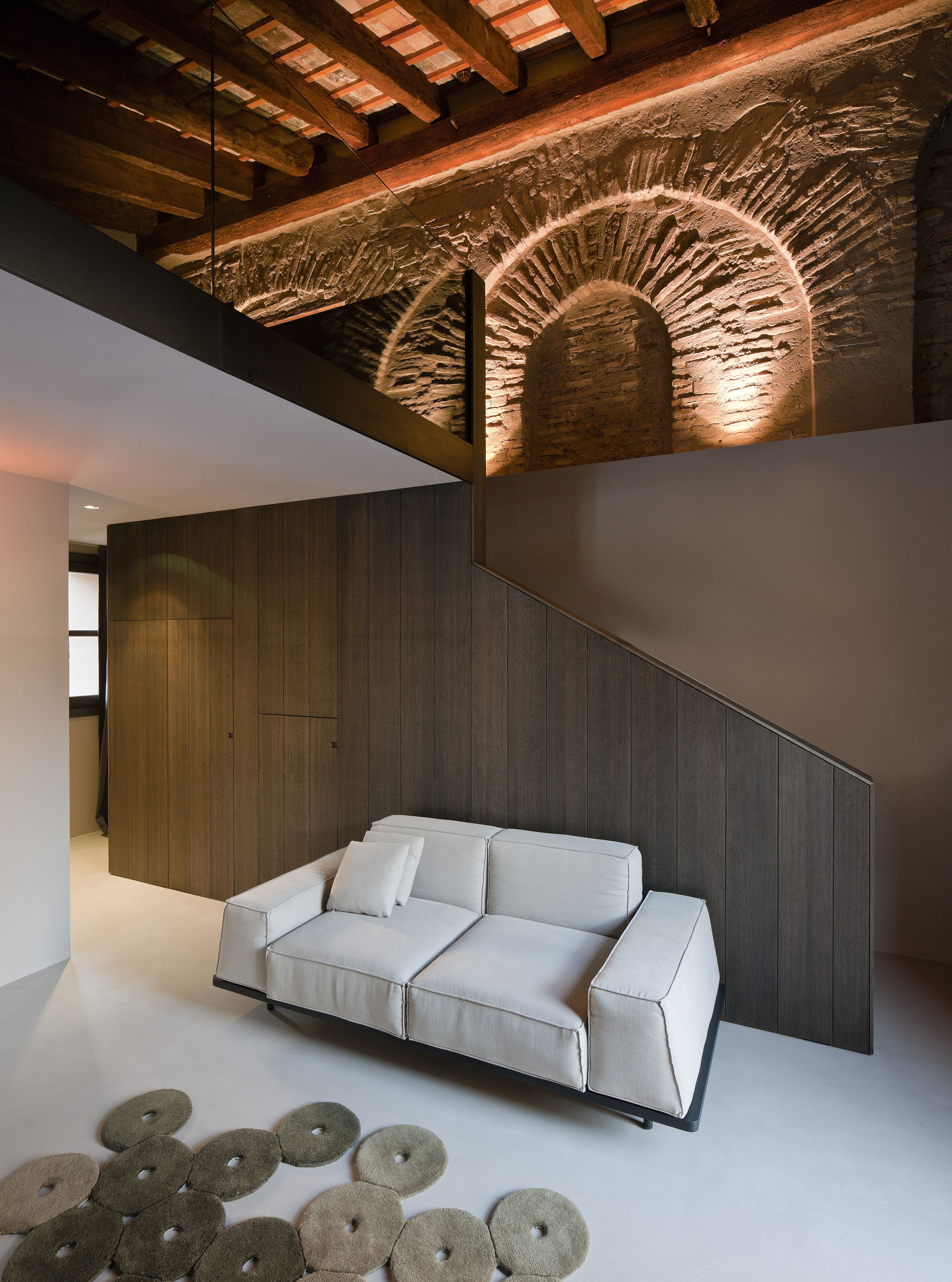 Um interior moderno com sofá, painéis de madeira nas paredes e um design de teto singular.