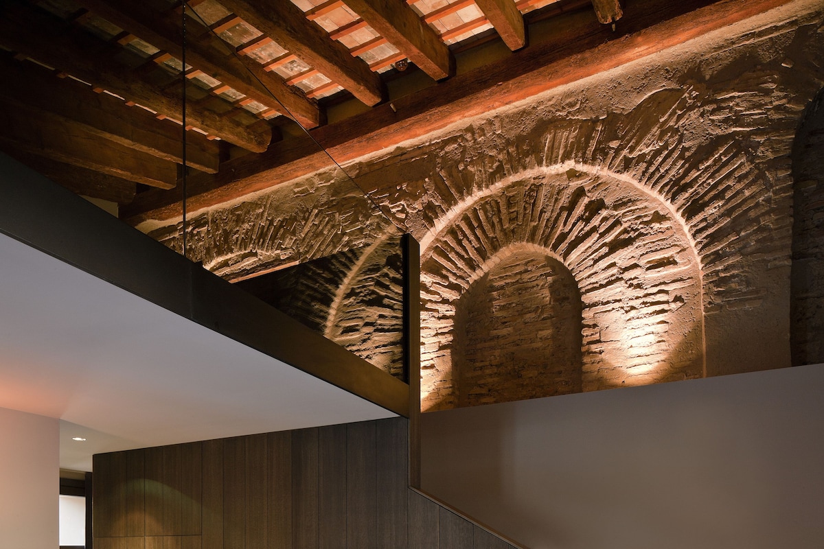 A modern interior with a sofa, wooden panel walls, and a unique ceiling design.