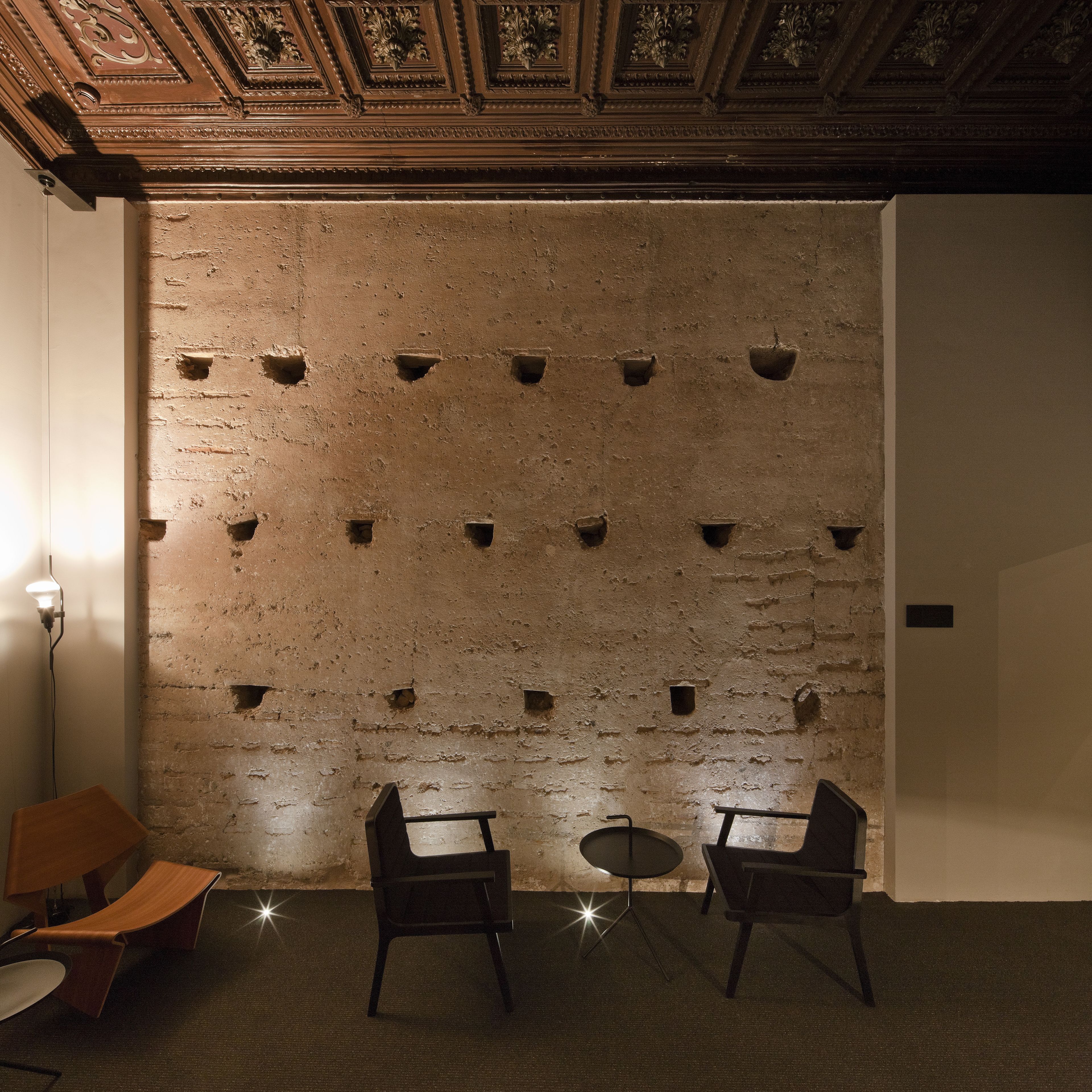 A room with a brick wall, two chairs, a small table, and a light fixture.