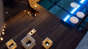 Een zwembadgedeelte met houten terrassen, zitplaatsen en een grote lamp.