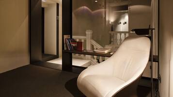 A modern room with a unique curved chair, a glass partition, and a small table with books.