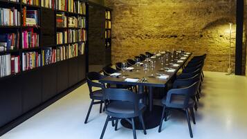A conference room with a long table, chairs, and a bookshelf filled with books.