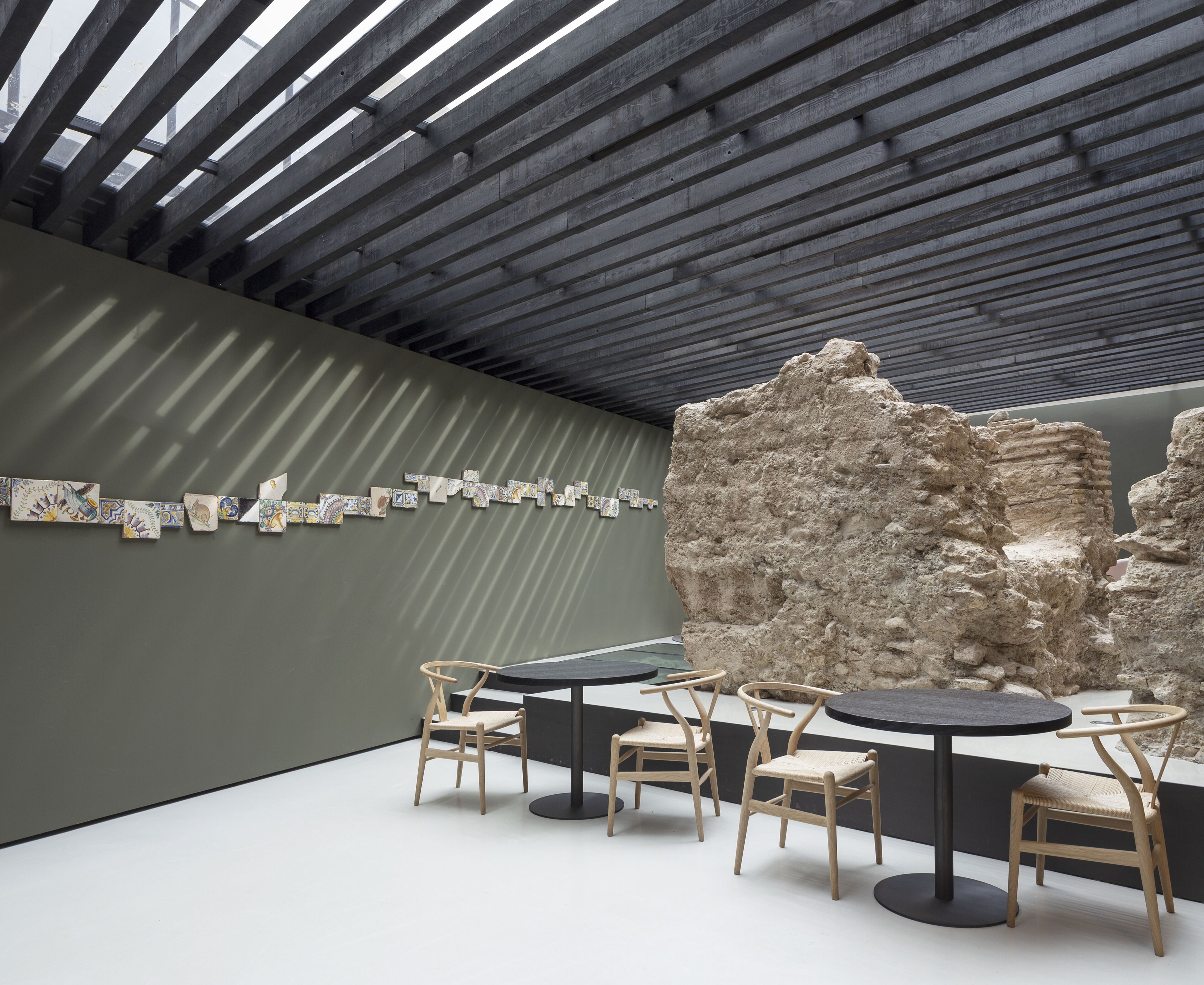 Un espai interior amb un disseny modern, que presenta una sèrie d'obres d'art a la paret, una gran escultura de roca i una zona de seients amb taules i cadires.