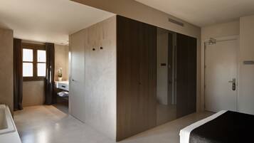 Habitación de hotel moderna con un armario amplio, baño con bañera y un espacio separado para el inodoro.
