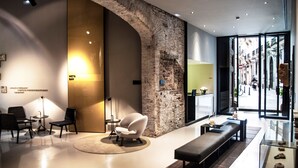 Een moderne lobby met een stenen boog, een zithoek en een glazen vitrine.