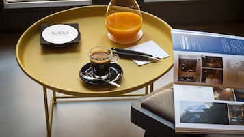A yellow table with a coffee cup, a glass of orange juice, a pen, and a booklet.