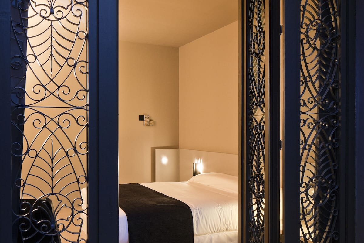 Una habitación de hotel con una cama, una mesita de noche y un velador.