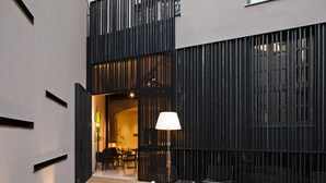 Een modern buitenverblijf met tafels, stoelen, een lamp en uitzicht op het interieur.