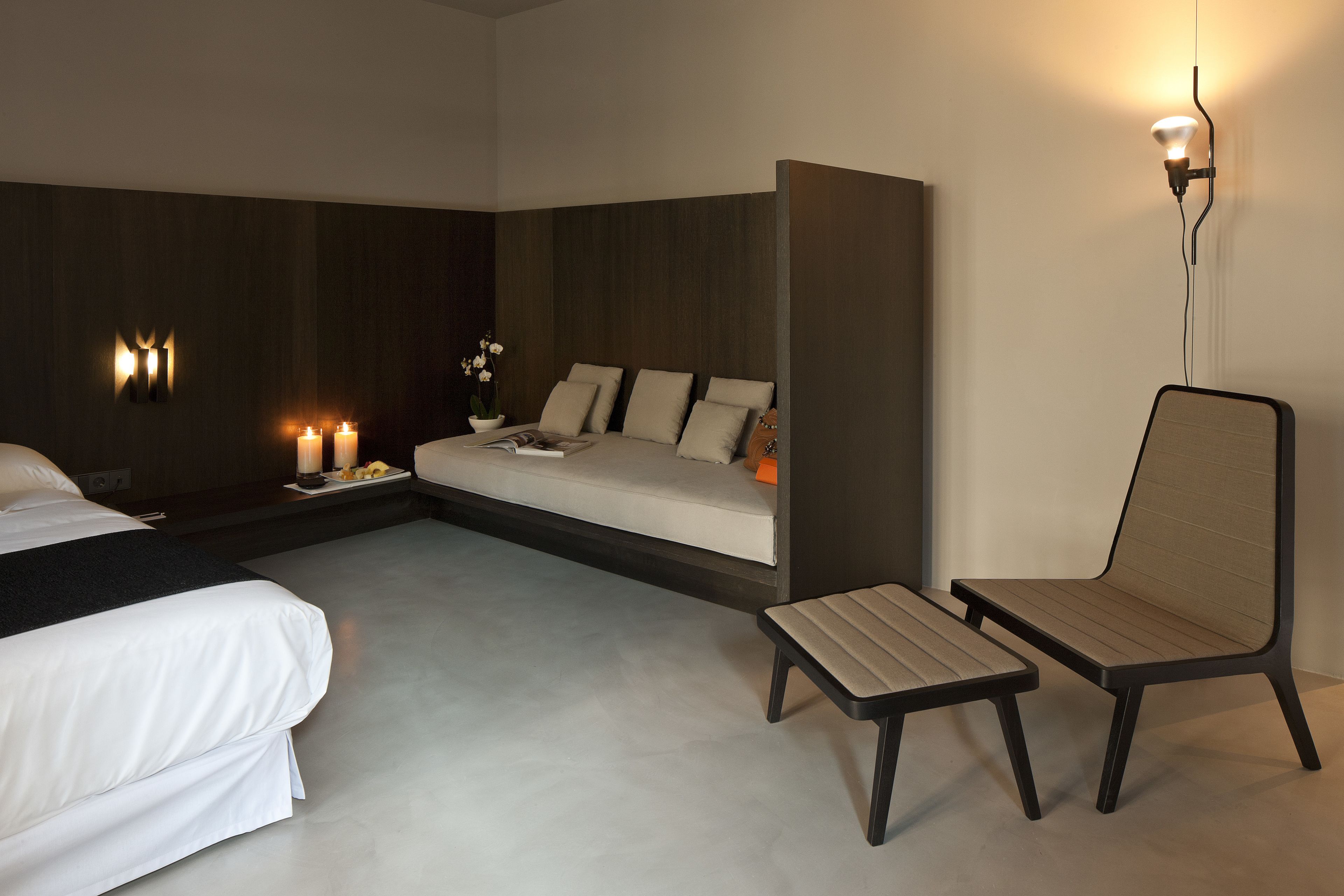 Een moderne hotelkamer met een bed, een slaapbank, een klein tafeltje, een stoel en wandlampen.
