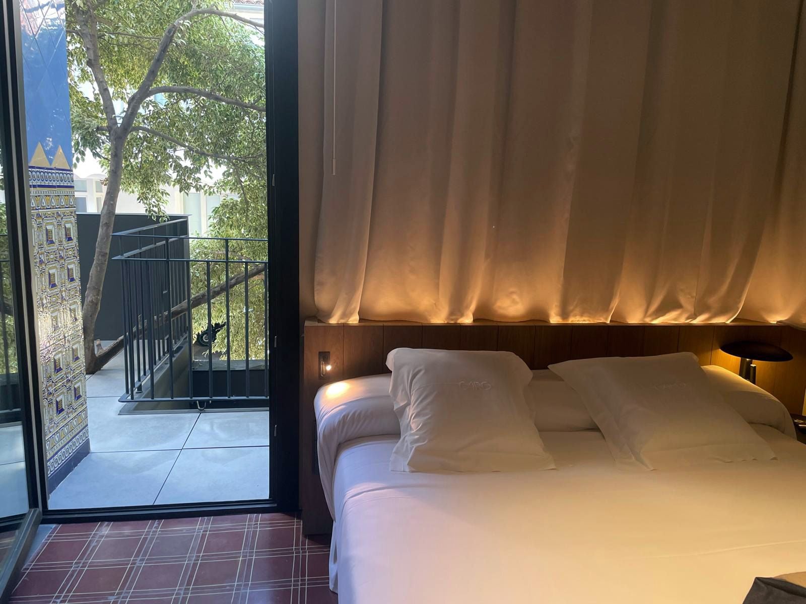 Una habitación de hotel con cama, vistas a un balcón y una puerta que da al exterior.