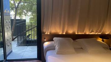 Una habitación de hotel con cama, vistas a un balcón y una puerta que da al exterior.