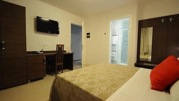 A hotel room with a bed, a desk, a chair, a television, and a wardrobe.