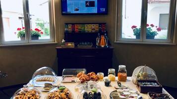 A buffet table with various food items and a television displaying a news channel.
