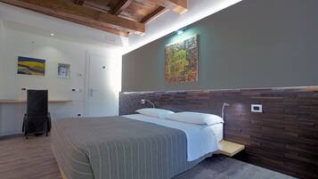 A bedroom with a wooden headboard, a bed with a striped bedspread, a bedside table, a chair, and artwork on the walls.