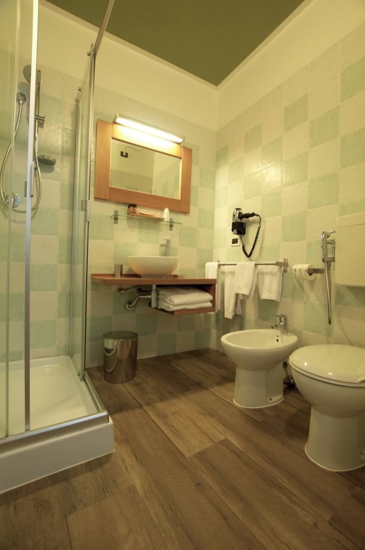 Un baño con cabina de ducha de vidrio, un lavamanos con espejo, un bidé y un inodoro.