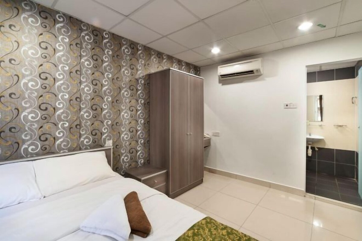 A bedroom with a bed, wardrobe, and a bathroom with a mirror and sink.