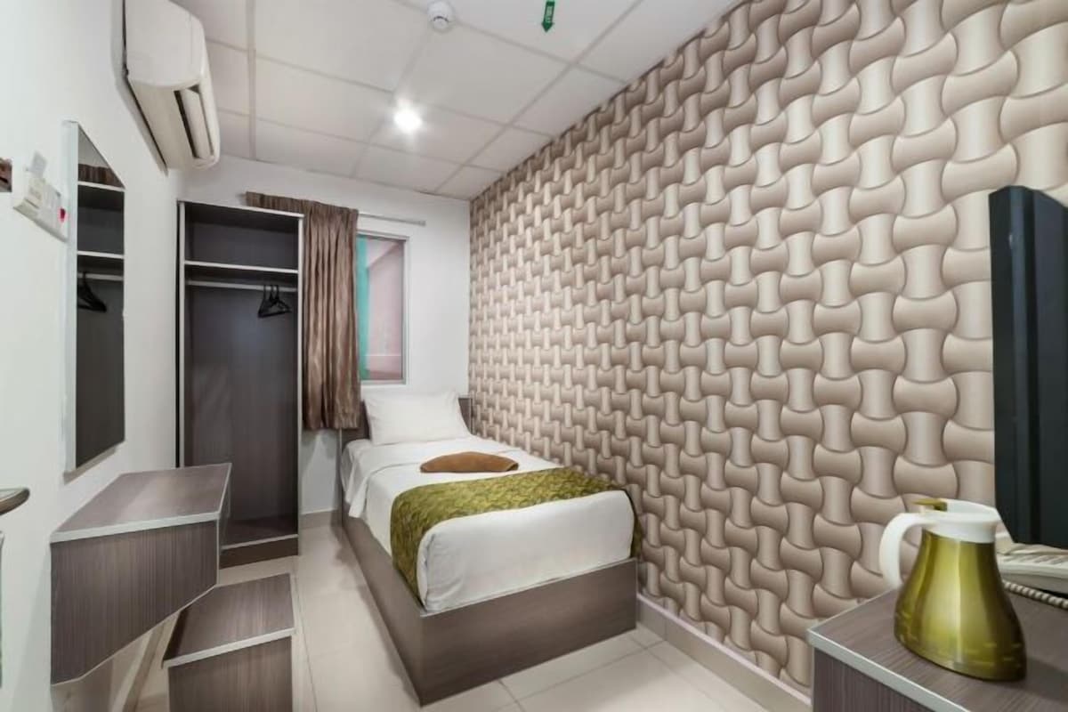 A bedroom with a bed, a wardrobe, a mirror, a bedside table, and a wall with a textured pattern.