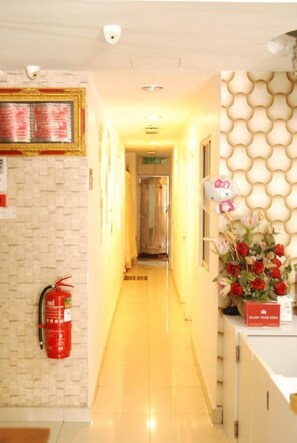 A hotel reception area with a reception desk, a fire extinguisher mounted on the wall, a Hello Kitty decoration, and a floral arrangement. - LaComme Inn (Kuala Lumpur)