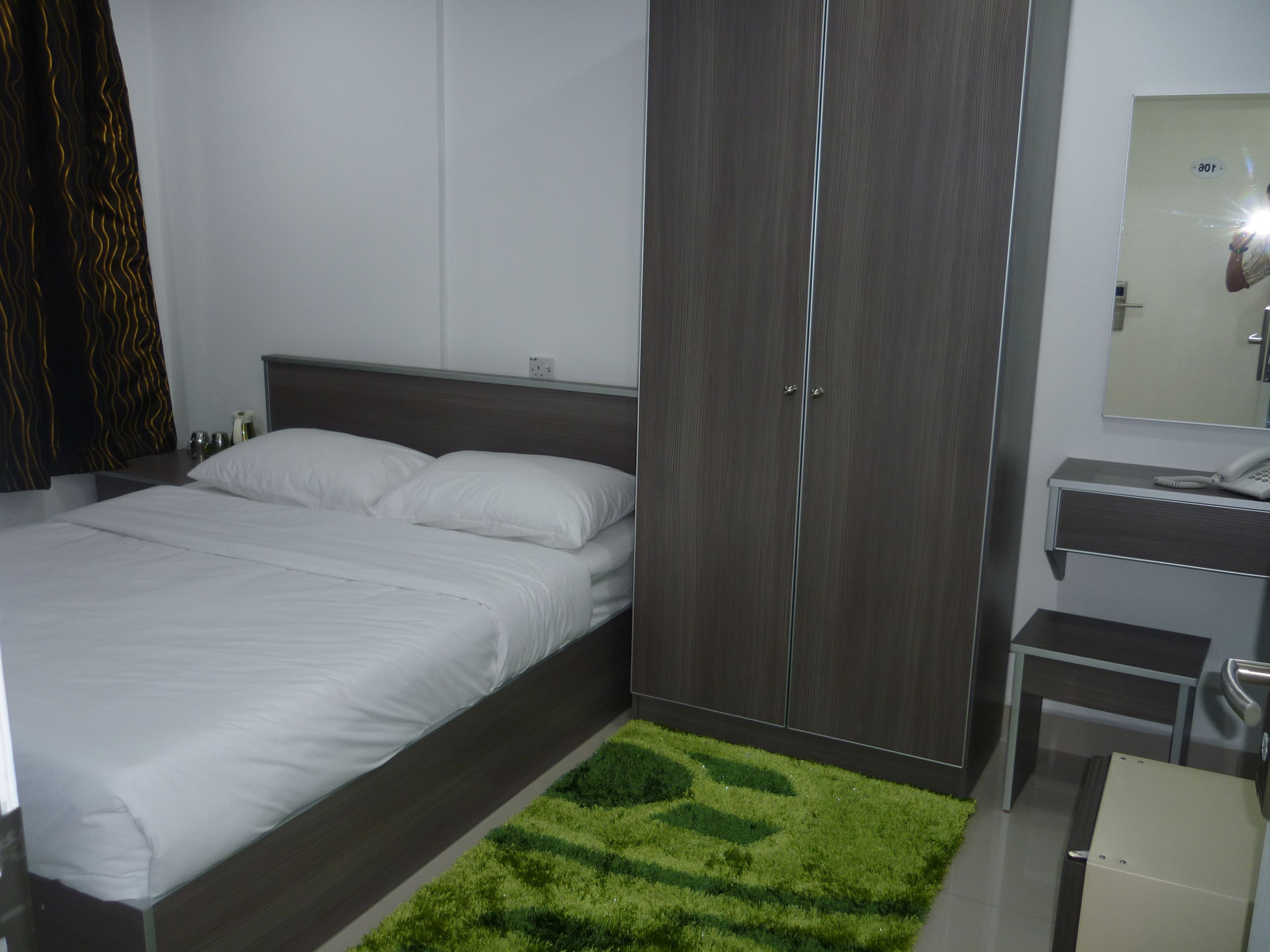 A modern bedroom with a bed, wardrobe, and a small desk with a telephone.