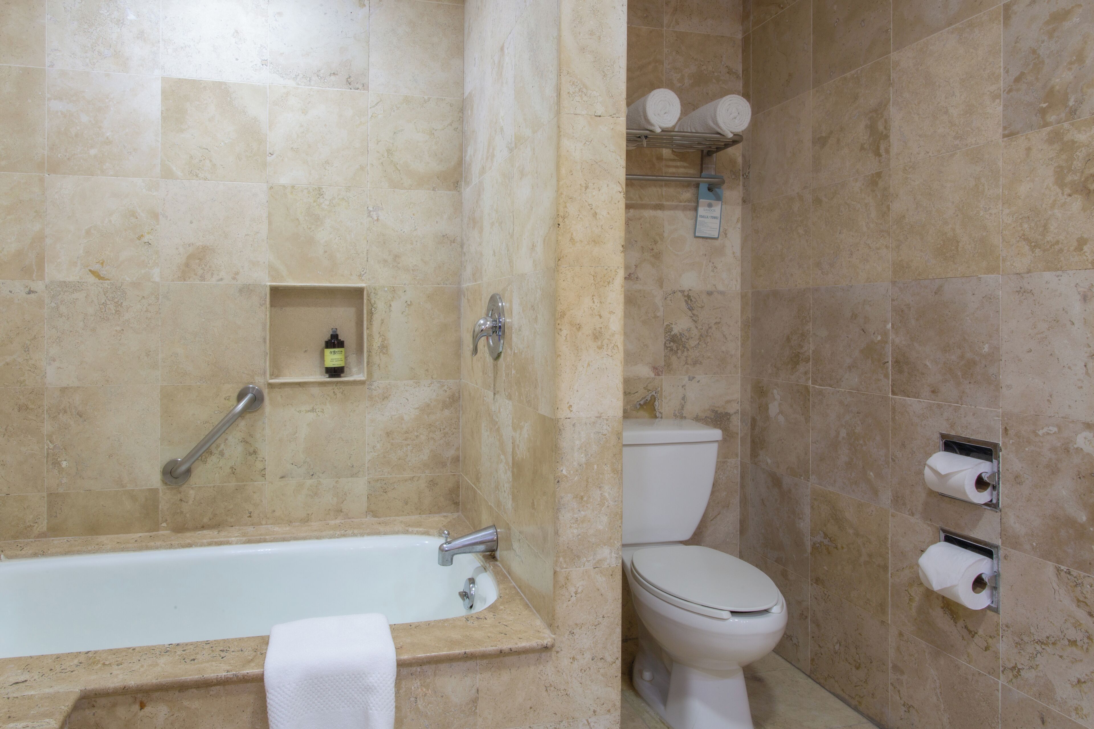 A bathroom with a bathtub, toilet, and towel rack.