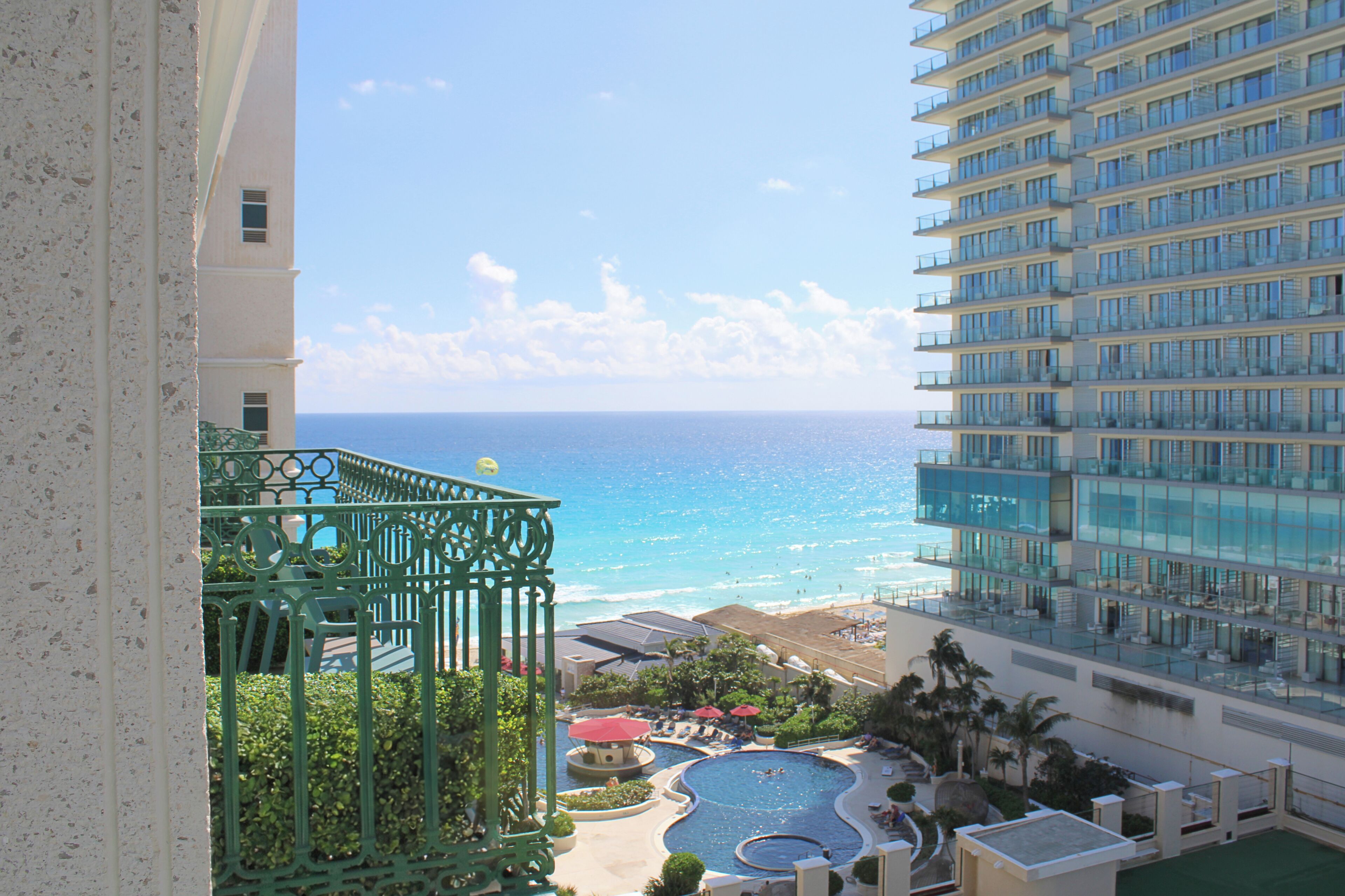 A high-rise hotel with a view of the ocean and a pool area.