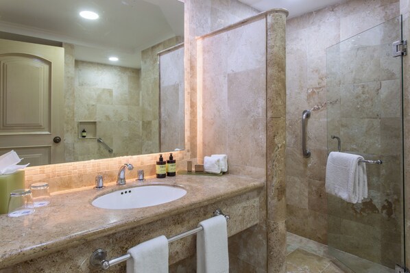 Un baño con lavamanos, espejo y cabina de ducha de vidrio.