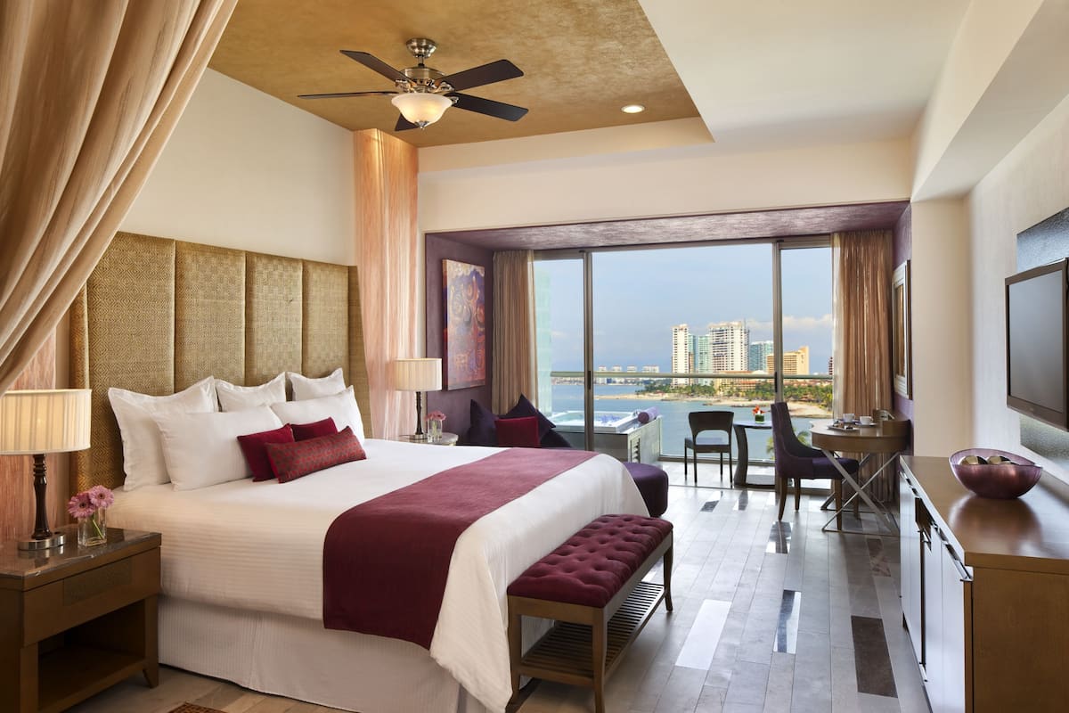 Ein Hotelzimmer mit einem großen Bett, einem Schreibtisch, einem Stuhl und Blick auf die Stadt.
