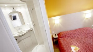 A hotel room with a white bathroom, a red bed, and a small bedside table with a remote control. - Hotel Premiere Classe Pau EST Bizanos (Bizanos)