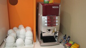 A Nescafé coffee machine with a selection of coffee pods and a tray of white cups. - Hotel Premiere Classe Pau EST Bizanos (Bizanos)