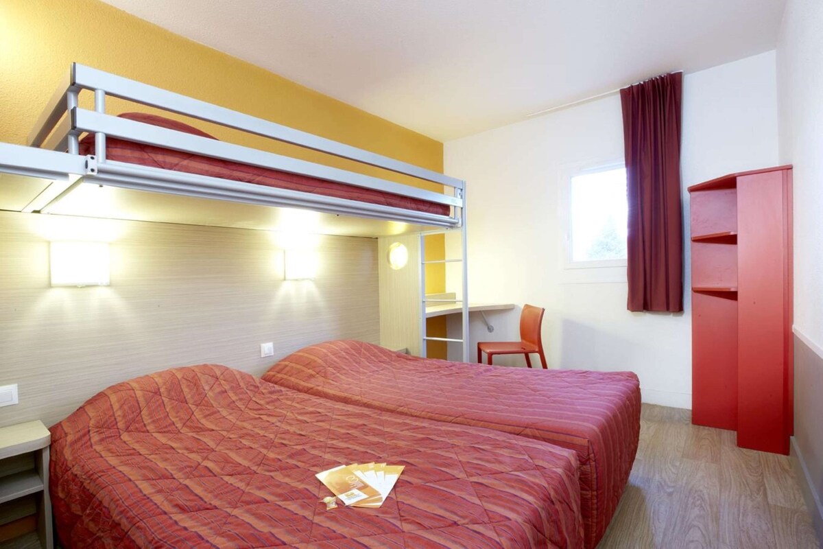 Ein Zimmer mit zwei Betten, einem Schreibtisch, einem Stuhl und einem Kleiderschrank.