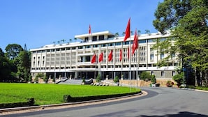 A large, modern building with multiple red flags, a well-maintained lawn, and a curved driveway leading to the entrance. - Grand Silverland Hotel & Spa (Ho Chi Minh City)