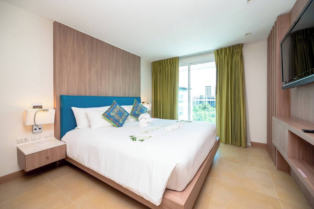 Une chambre d’hôtel moderne avec un grand lit, une télévision et une fenêtre avec des rideaux.