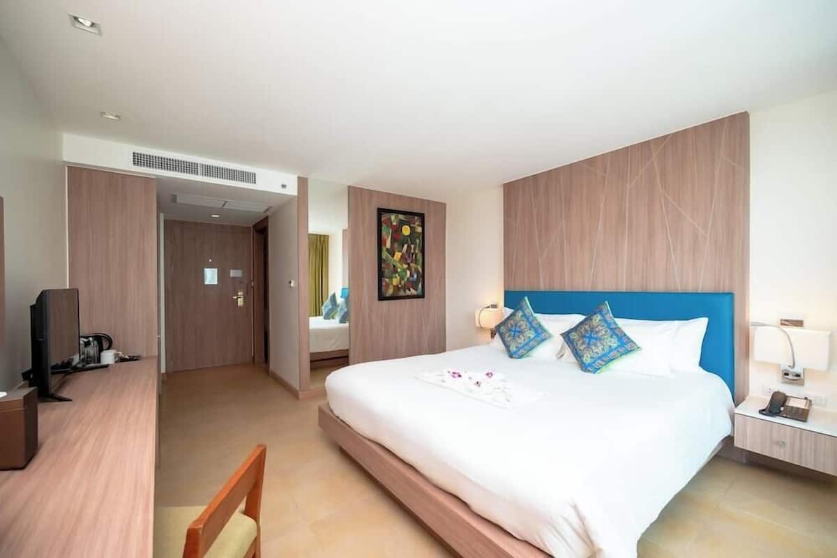 Une chambre d’hôtel avec un lit, un bureau, une chaise, une télévision et un tableau au mur.