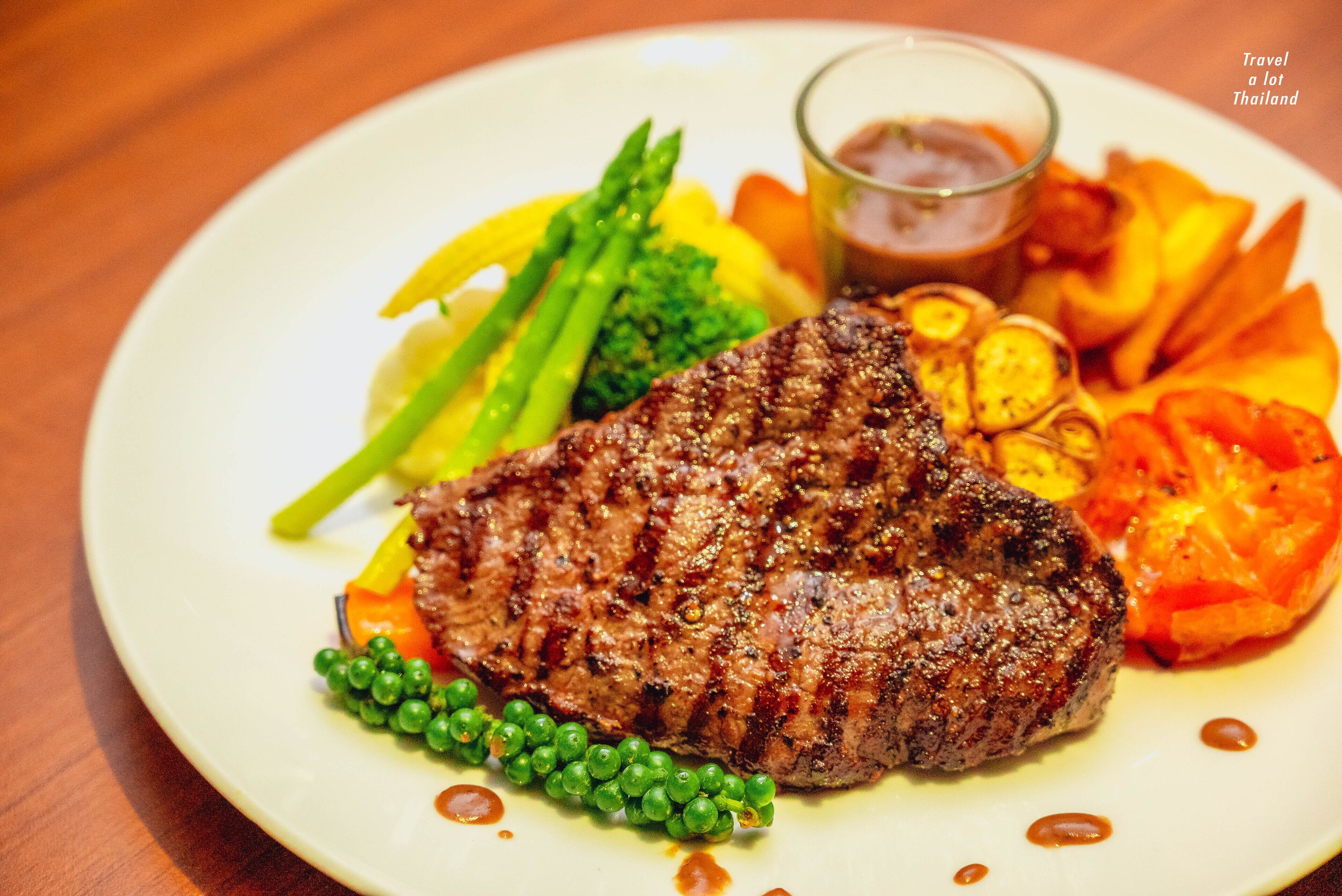 Um prato com bife grelhado, aspargos e legumes assados.