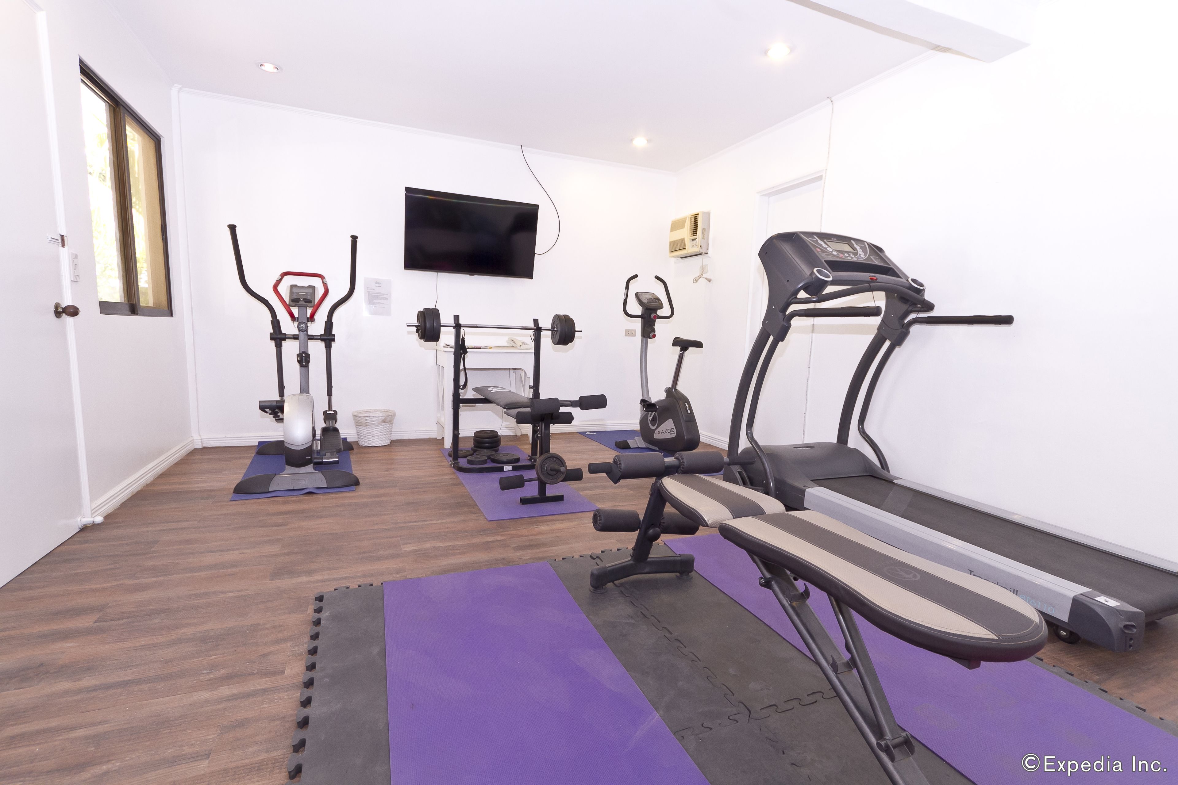 A home gym with a treadmill, elliptical, and weight bench.