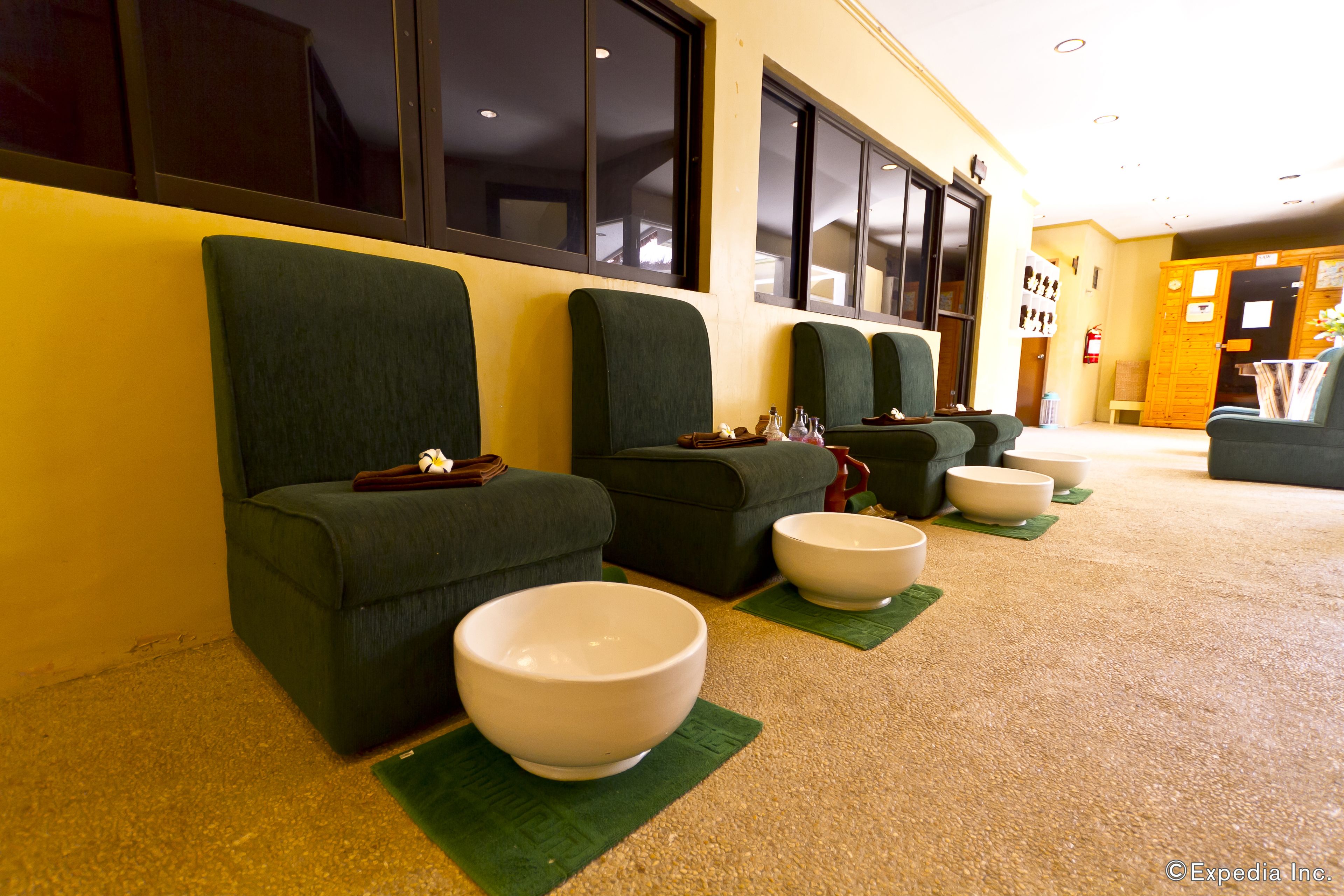 A row of green chairs with bowls on green placemats, a fire extinguisher, and a wooden door in a hallway.