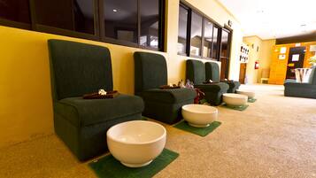 A row of green chairs with bowls on green placemats, a fire extinguisher, and a wooden door in a hallway.