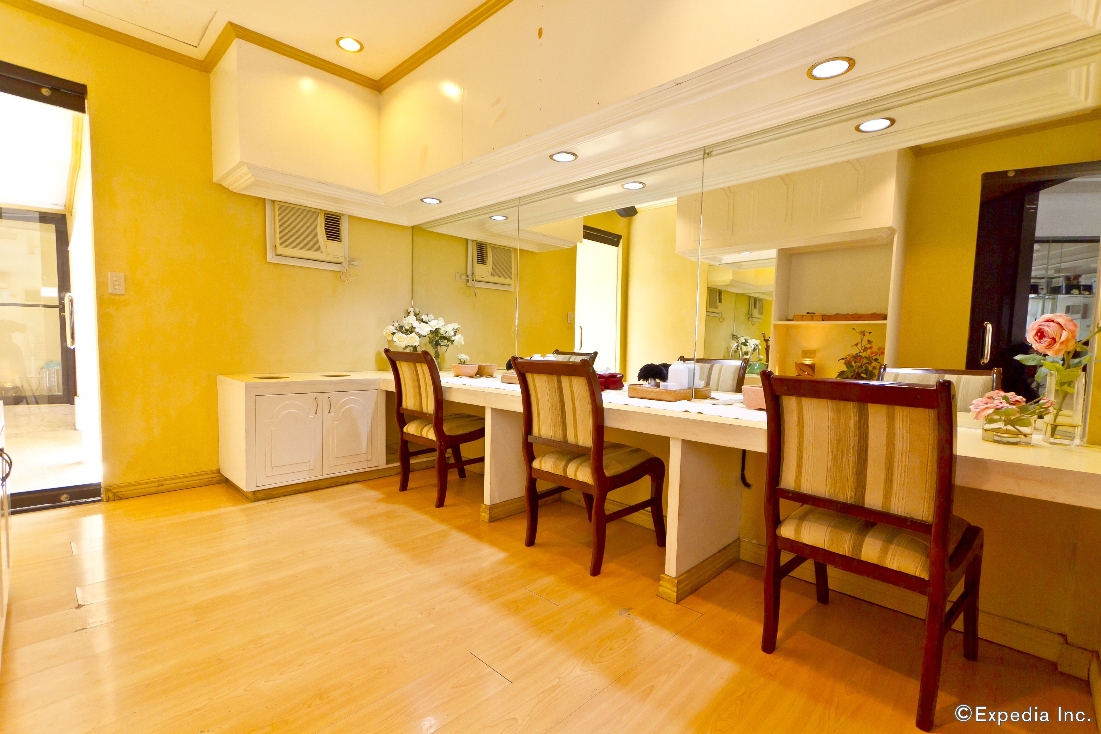 A dining area with wooden chairs and a white table, yellow walls, and a wooden cabinet.