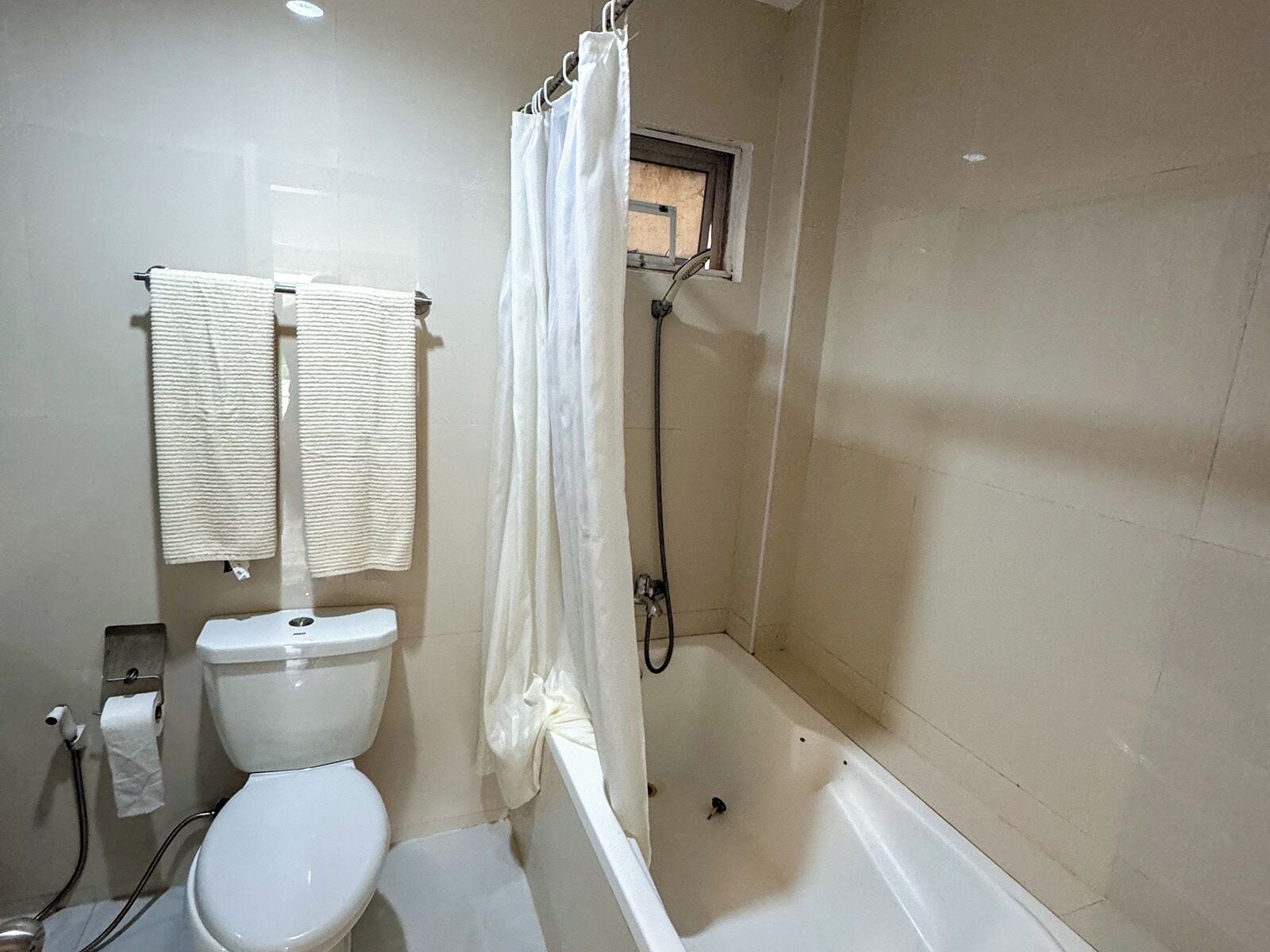 A bathroom with a toilet, a bathtub, and a shower curtain.