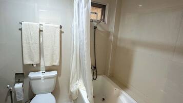 A bathroom with a toilet, a bathtub, and a shower curtain.
