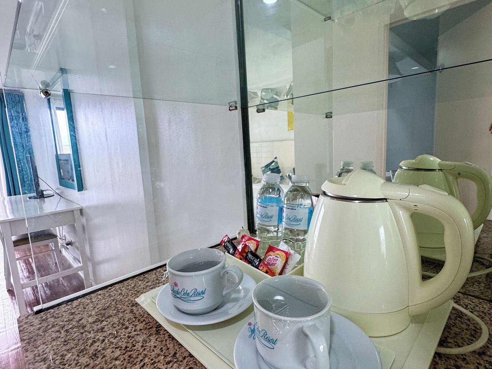 A kitchenette with a coffee maker, two cups, and bottled water.