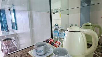 A kitchenette with a coffee maker, two cups, and bottled water.